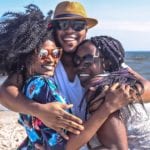 THree people hugging on a beach.