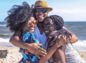 THree people hugging on a beach.